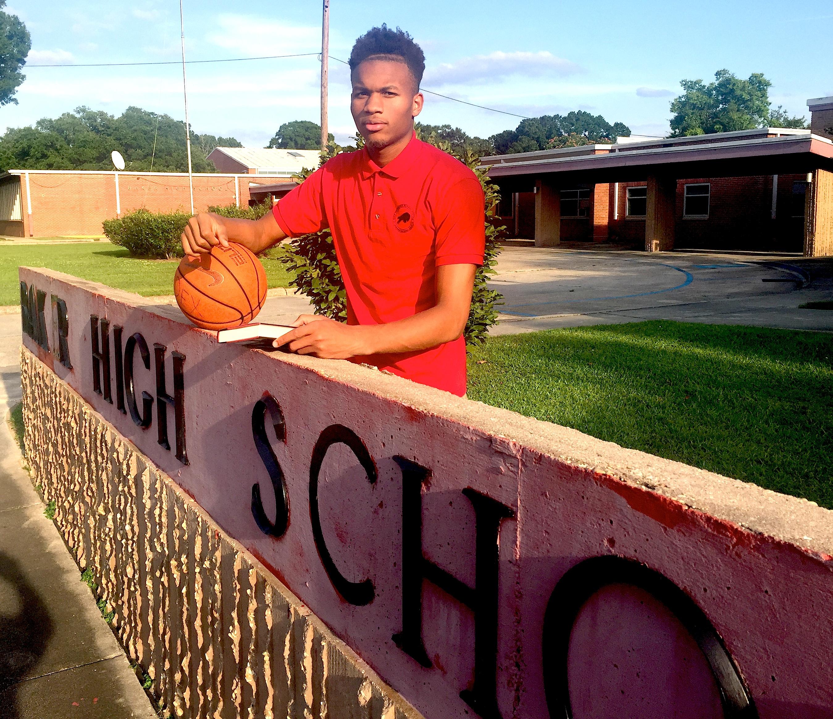Photo of Baker High School Basketball MVP, Dexter Dennis standing in front of the high school