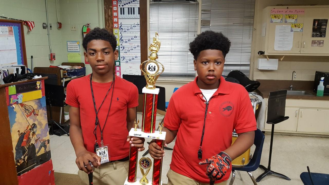 Two Baker Middle Band Students hold winning trophy from battle of the bands