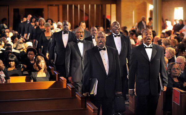 A photo of Heritage Choral Ensemble marching down a church aisle to sing a concert of Negro Spirituals