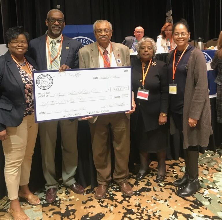 A photo of the Baker School System Board Members a the Louisiana School Board Annual Conference receiving a big check from the foundation for $50,000.