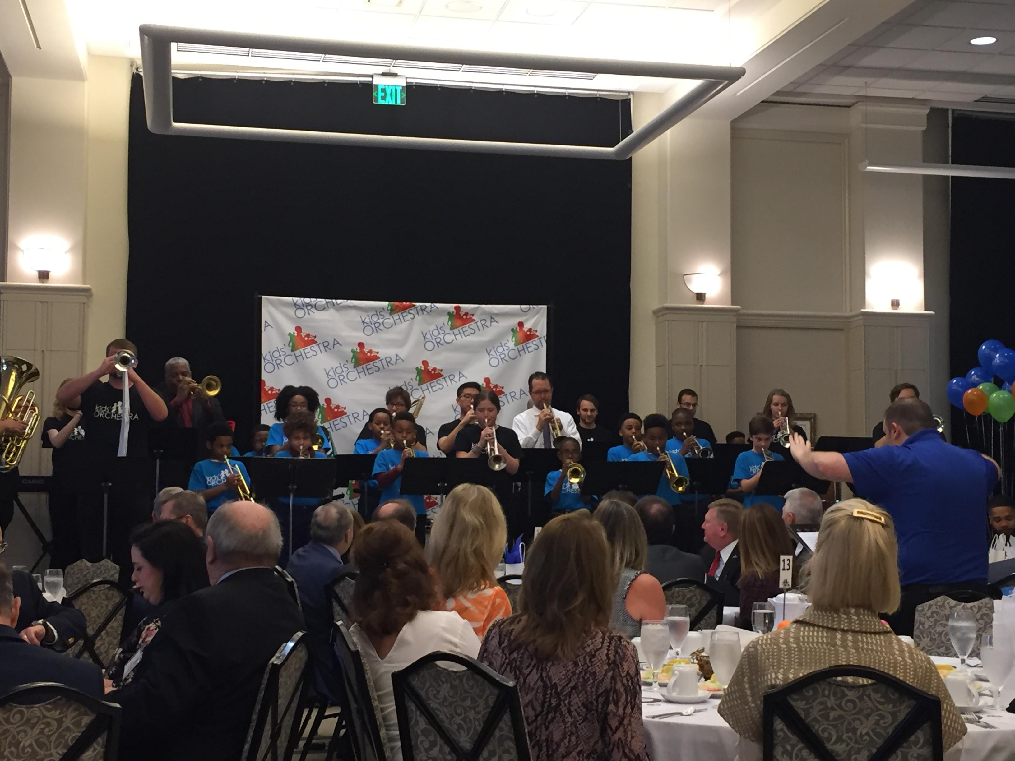 A photo of the a kids orchestral wind ensemble performing at the annual breakfast