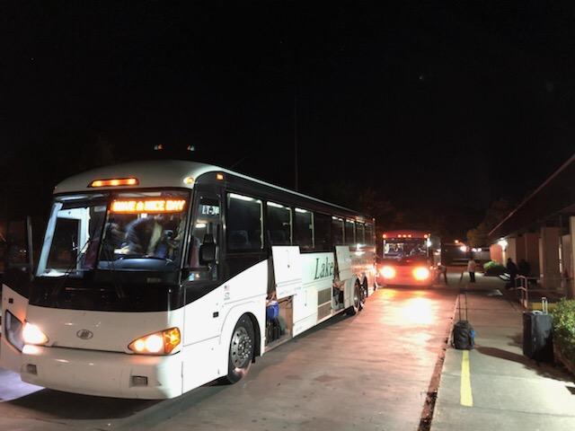 A photo of the Baker High School Band loading a charter bus to travel to Florida for a national competition
