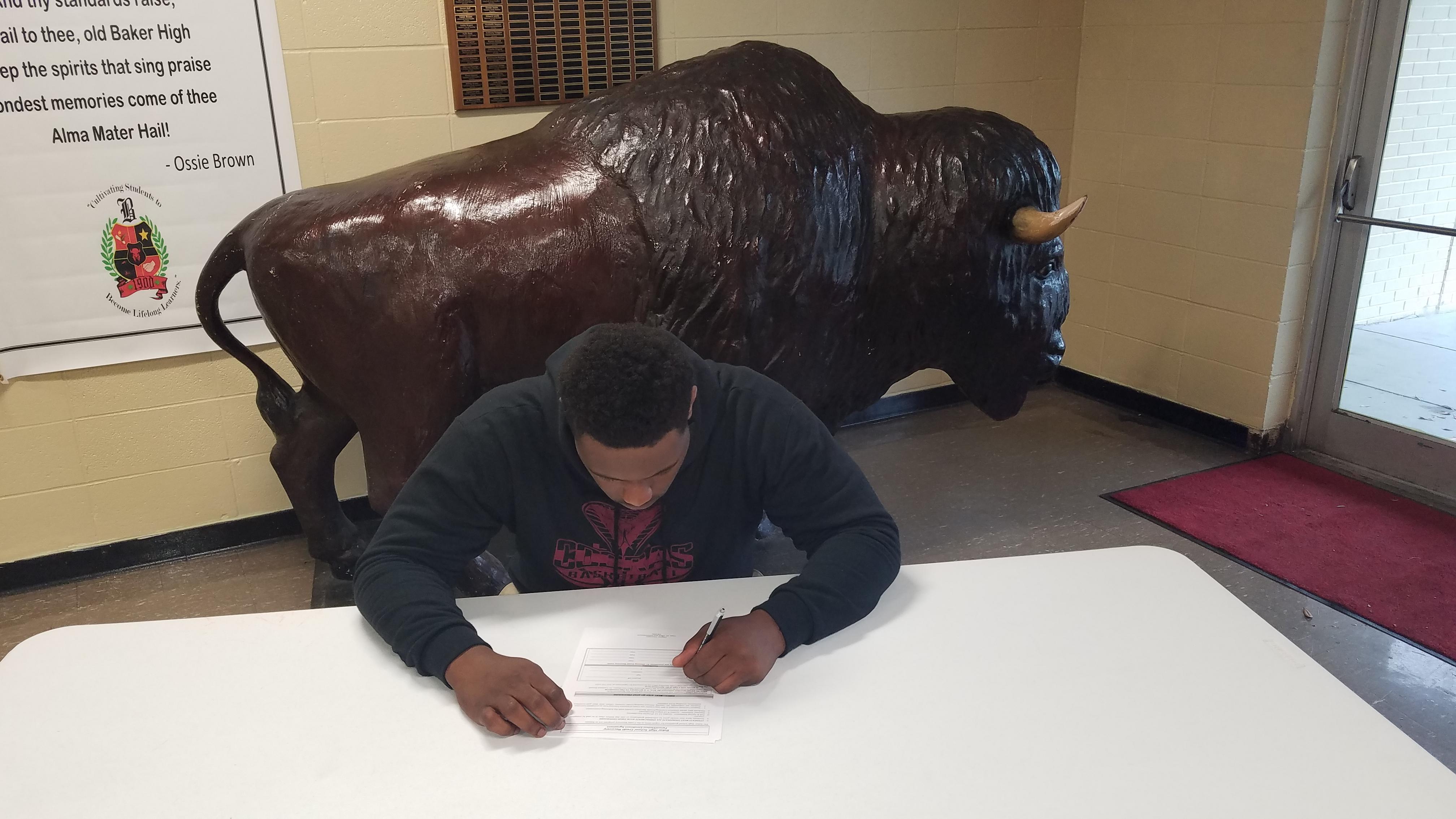 a photo of Baker High School Athlete, Jalen Gross, signing a commitment to play football for East Central Mississippi Community College