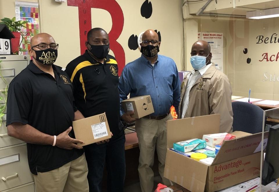 a photo of 4 members of Xi Nu Lambda Alpha Phi Alpha who presented gift of PPE to Baker Middle School